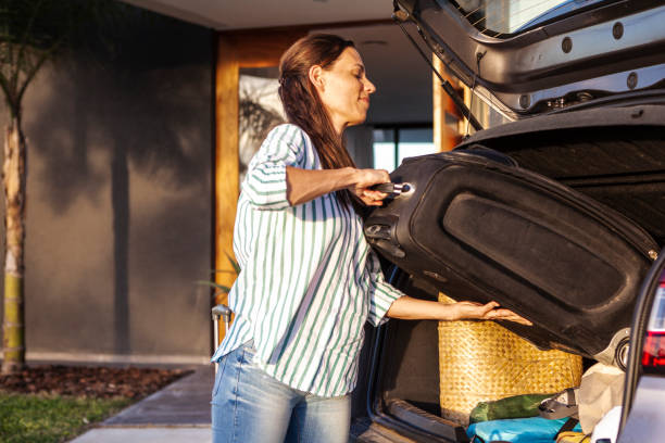 istock Woman loading luggage in car boot 1293417886