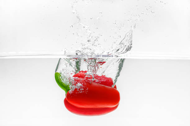 Close up view of red pepper in water with drop splash isolated on white background with copy space