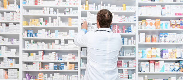 apotheker überprüft ein arzneimittel in regalen in einer apotheke drogerie - apotheke stock-fotos und bilder