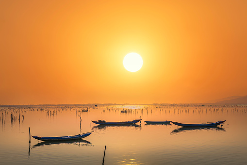 Fishing boat in the big lagoon at sunset sky. This is the main means of transportation to catch fish of fishermen in central Vietnam