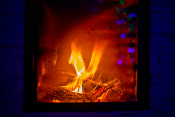 indistinct burning fire in the fireplace through the fire glass with reflective lanterns, horizontal format