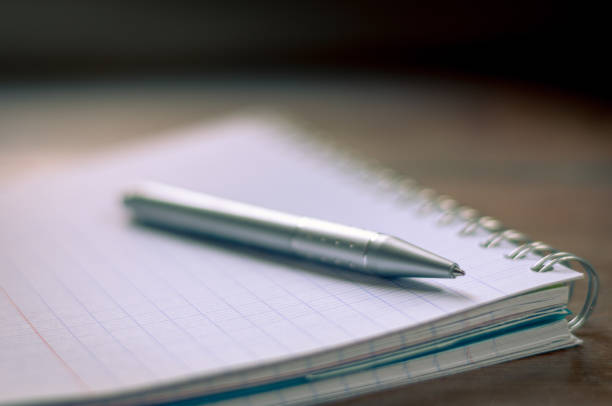 istock Ball point pen on spiral note pad.very selective focus,only the pen nib is in focus,background 1293429228