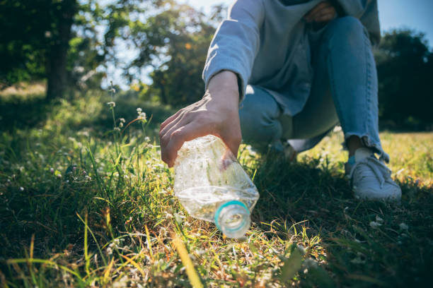 frau hand halten müllflasche kunststoff setzen in recycling-tasche für die reinigung - nature parks stock-fotos und bilder