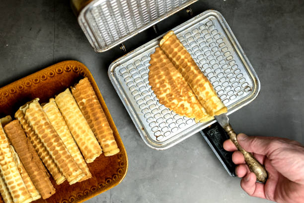 istock Cooking waffles at home - waffle maker. A man's hand rolls a wafer. Ready-made waffles on a plate. Culinary background. Step-by-step instructions. step 3 1293432542