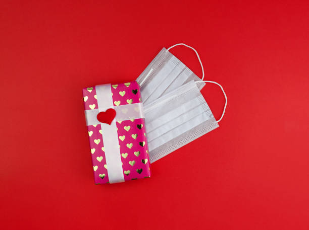 istock Gift box in pink packaging with hearts. Celebrating Valentine's Day or romantic date during lockdown 1293435392