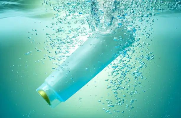 Photo of White can in blue water with bubbles in the tank. Copy space.