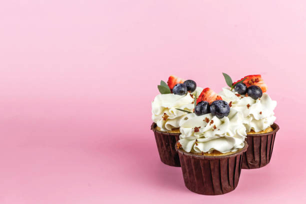 köstliche cupcakes mit sahne und frischen beeren isoliert auf rosa hintergrund. kopieren sie den speicherplatz. - muffin cake isolated small stock-fotos und bilder