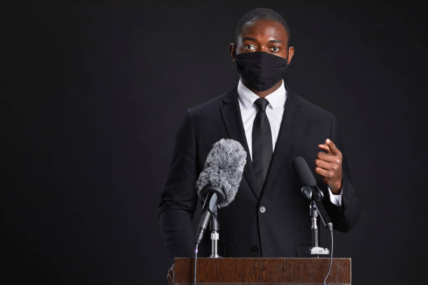 istock Official Speaking to Microphone Wearing Mask 1293444840