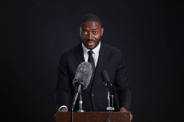 Microphone and Gavel Resting on a Table with the American Flag Painted On A Brick Wall Behind.