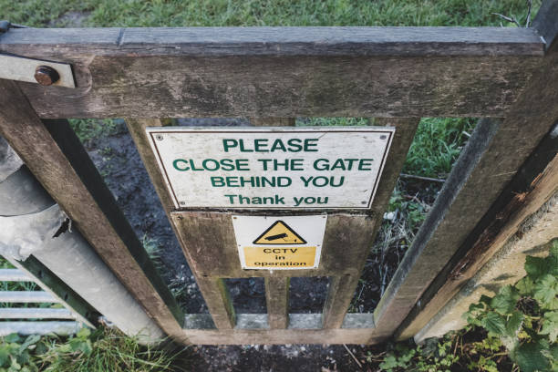 Improvised Close The Gate and CCTV signs seen attached to a wooden gate on the entrance to a community allotment area. The wooden gate is spring loaded and provides access to the allotment holders. community garden sign stock pictures, royalty-free photos & images