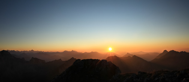 Amazing colorful Sunset or Sunrise above Mountain Ranges with clear sky. Alps, Allgau, Bavaria, Germany.