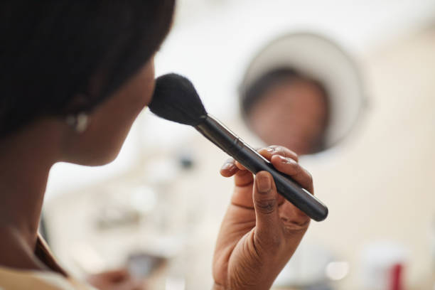 istock Young African-American Woman Putting On Blush 1293446908