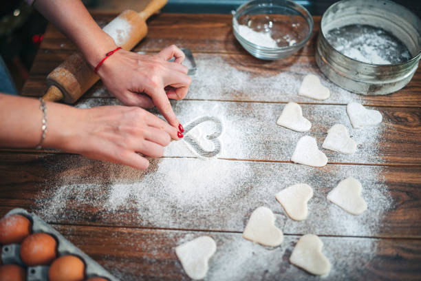 Woman drawing heart symbol in flour on wooden table Woman hands drawing heart symbol in flour on wooden table. She makes heart shape cookies for Valentines day circa 14th century photos stock pictures, royalty-free photos & images