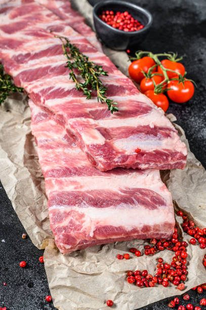 istock Fresh raw pork ribs with spices and herbs. Black background. Top view 1293451551