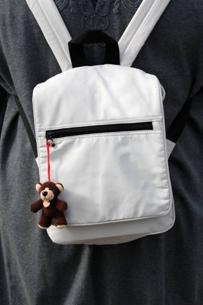 Light grey small unisex classic vintage retro design backpack made of durable water resistant polyester with zipper closure and small miniature plush bear pendant key ring