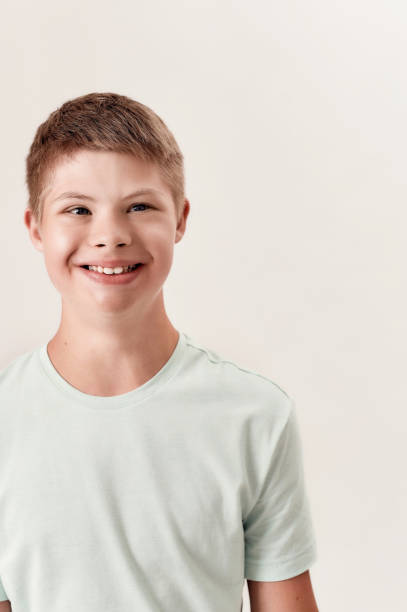 istock Portrait of cheerful disabled boy with Down syndrome smiling aside while posing isolated over white background 1293455809