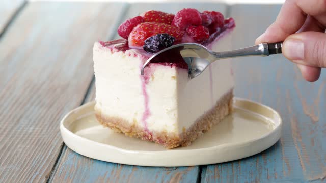 Cutting cheese cake with berries