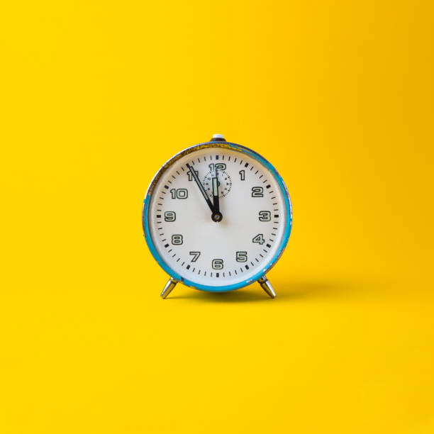 istock Old blue analog clock on a yellow background. It's 11.55 o'clock. New year. Square photo. 1293459713