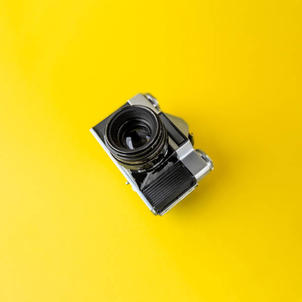 istock Old analog camera on a yellow background. Analog photography. Copy Space. Square photo. 1293459918
