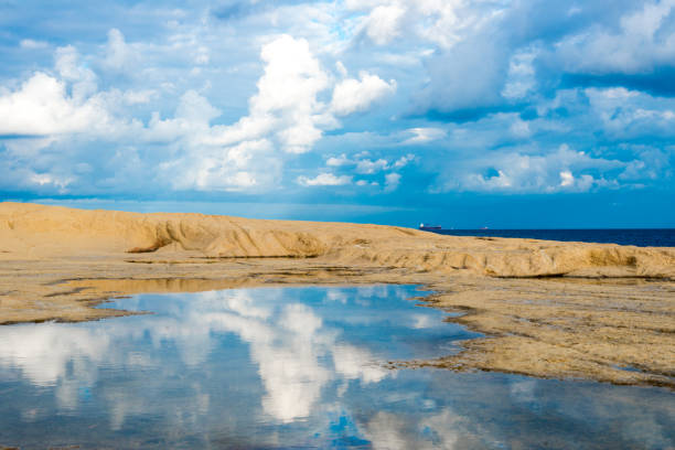 Small bay of sand and sandstone with clouds reflected in the water