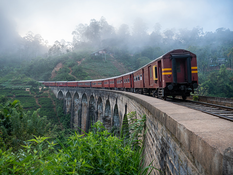 Red train passing on famous nine arch bridge viaduct in Sri Lanka, Ella