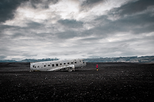 Tourist in red photographing Solheimasandur Plane Wreck in Iceland