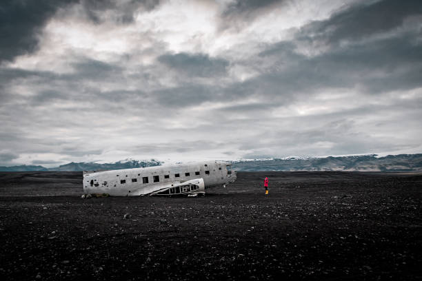 tourist in red photographing solheimasandur plane wreck - tourist photographing armed forces military imagens e fotografias de stock