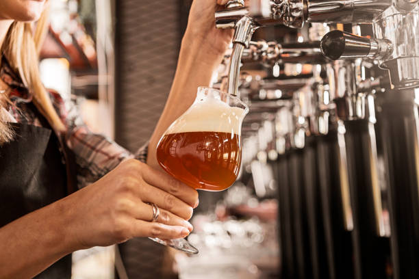рука женщины-бармена на пивном кране в баре - beer bar counter bar beer glass стоковые фото и изображения