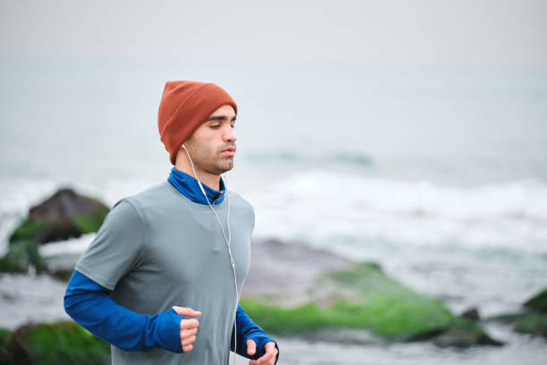 istock 20-24 years old men running at coastline on cold temperature 1293469825