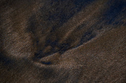Close-up abstract brown sea sand dune background on the seashore in nature. Selective focus.
