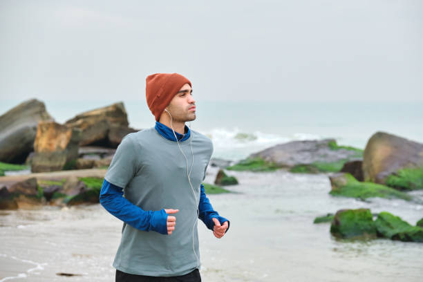 istock 20-24 years old men running at coastline on cold temperature 1293469876