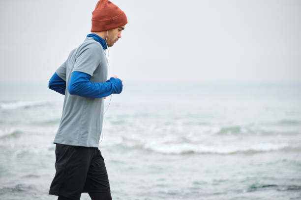 istock 20-24 years old men running at coastline on cold temperature 1293469896