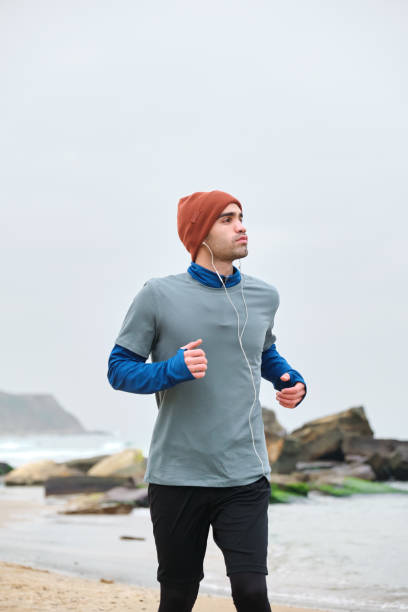 istock 20-24 years old men running at coastline on cold temperature 1293469966