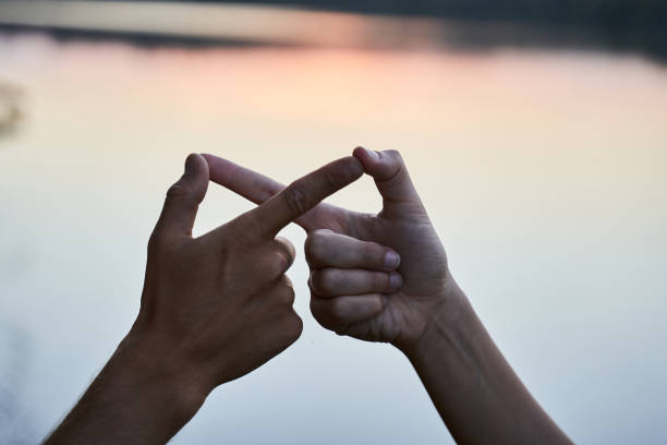 Couple making infinity symbol Close up view of couple in love gesturing infinity with fingers. Man and woman making infinity symbol with hands against bright sunshine bridge hand stock pictures, royalty-free photos & images