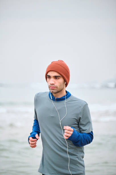istock 20-24 years old men running at coastline on cold temperature 1293470179