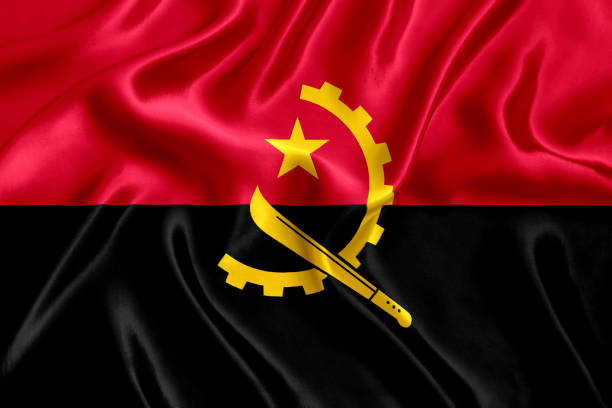 Flag of Angola waving in the wind. Blue sunny sky in the background. Horizontal orientation.