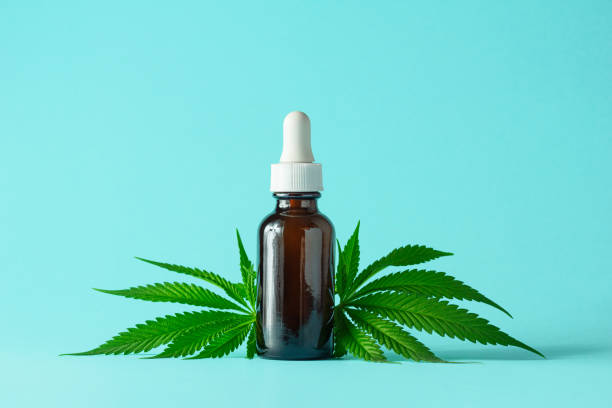 bottiglia di vetro di cbd o olio di thc con canapa o foglie di piante di cannabis medica isolate su sfondo acqua - blue medicine narcotic healthy lifestyle foto e immagini stock