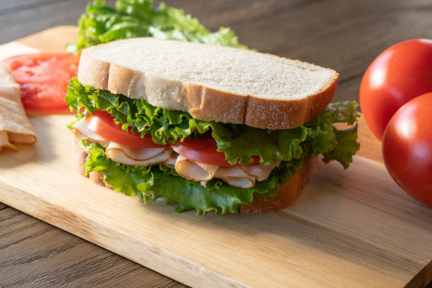 istock Turkey, lettuce and tomato sandwich on cutting board 1293478387