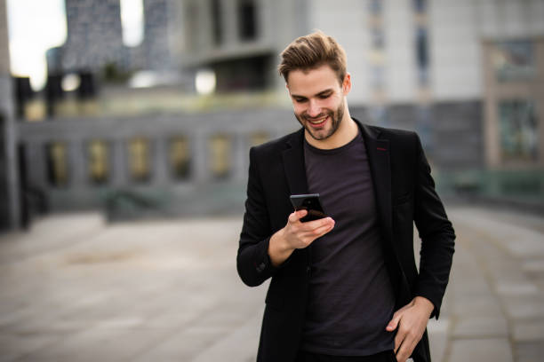 istock Young businessman using cell phone and drinking coffee in the city 1293478426