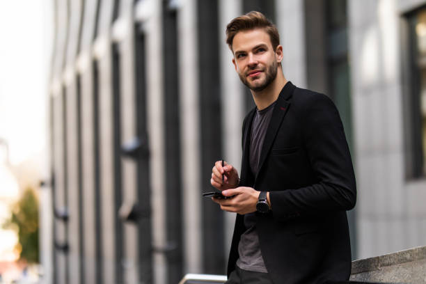 istock Attractive young businessman using his cell phone in street 1293478793