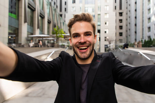 istock Beautiful businessman dressed in formal suit smiling at camera and taking selfie while standing outside 1293478850