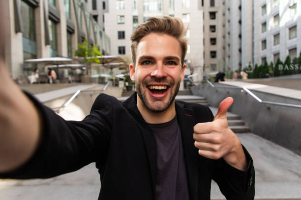istock Beautiful businessman dressed in formal suit smiling at camera and taking selfie while standing outside 1293478871