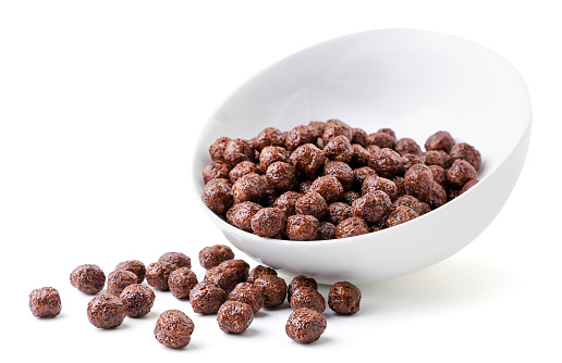 Cereal, chocolate balls spilled out from the plate close-up on a white background. Isolated.