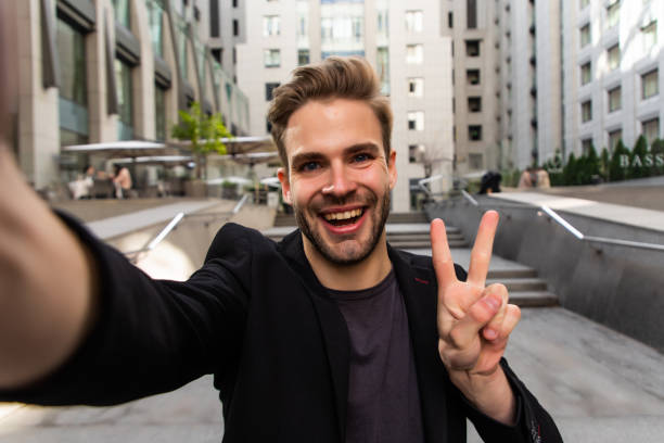 istock Beautiful businessman dressed in formal suit smiling at camera and taking selfie while standing outside 1293480718
