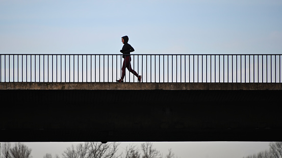 Duesseldorf, Germany, December 28, 2020 - Silhouette of a jogger on a bridge in Duesseldorf