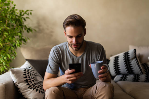 istock Young handsome man drinking coffee and using laptop while talking on phone. 1293487428
