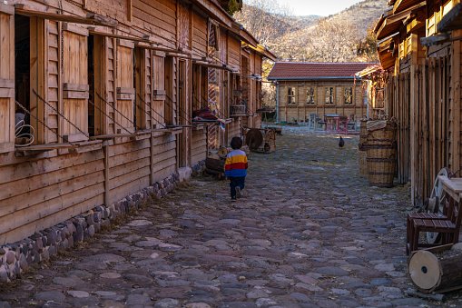 Köyün çarşısında koşturan renkli kazaklı çocuk. dükkanlar kapalı, sokaklar boş iken fotoğraflanmıştır