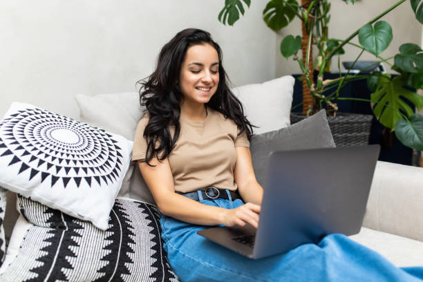 istock Happy woman using laptop sitting on cosy sofa 1293491393