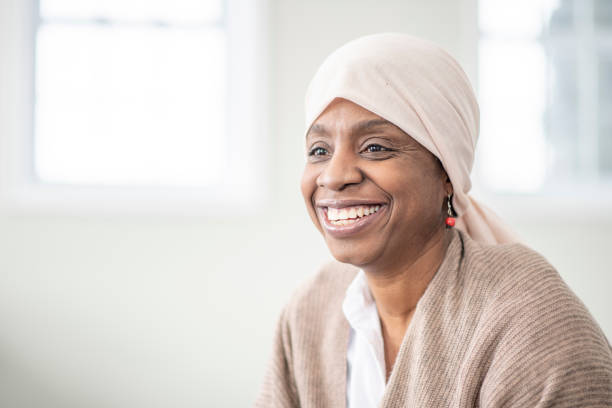 Happy to beat cancer! On her last day of chemotherapy, a female African American cancer patient smiles as she wears a headscarf to cover her hair loss. food chain stock pictures, royalty-free photos & images