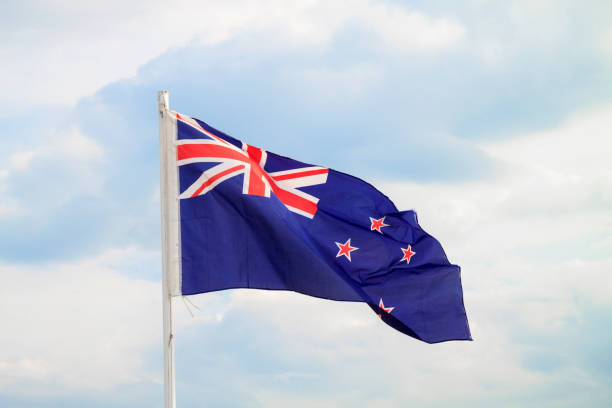 istock New Zealand flag on a blue sky with clouds background 1293493965